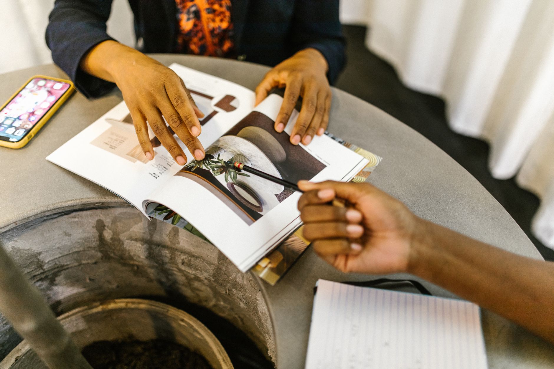 Deux personnes examinent les pages d’un magazine ouvert sur une table.