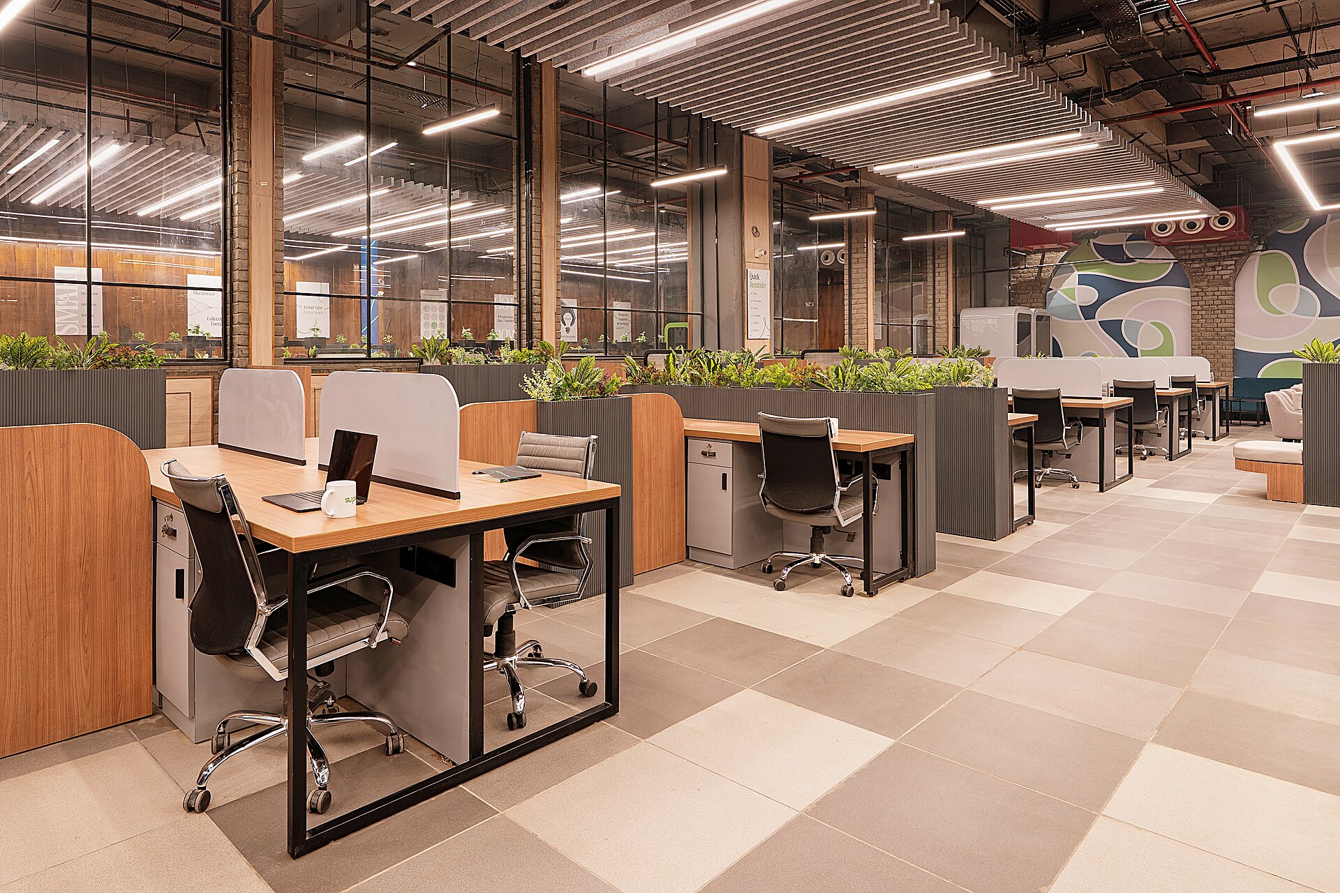 Plateau de bureaux en open space avec postes de travail vides, fauteuils noirs et plantes